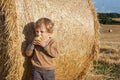 Little toddler eating apple with a big hay bale on field Royalty Free Stock Photo