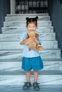 Little toddler girl in blue t-shirt holds brown dog toy Royalty Free Stock Photo