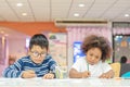 Little toddler girl and boy concentrate drawing together. Asian boy and Mix African girl learn and play together in the pre- Royalty Free Stock Photo