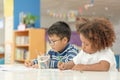 Little toddler girl and boy concentrate  drawing together.  Asian boy and Mix African girl learn and play together in the pre- Royalty Free Stock Photo