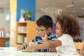 Little toddler girl and boy drawing together.  Asian boy and Mix African girl learn and play together in the pre-school class. Royalty Free Stock Photo