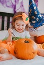 Little toddler girl drawing on a pumpkin making lantern jack on Halloween holiday. Little girl in a carnival costume