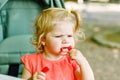 Little toddler girl eating red pepper and vegetables for healthy lunch snack sitting in baby stroller. happy child and Royalty Free Stock Photo