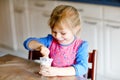 Little toddler girl eating yogurt for breakfast. Cute healthy baby sitting in the kitchen or at nursery and having meal. Royalty Free Stock Photo