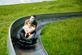 Little toddler girl and father having fun riding summer toboggan run sled down a hill. Active preschool child and dad Royalty Free Stock Photo
