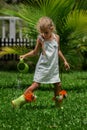 A little toddler girl girl is watering flowers in her green rubber boots Royalty Free Stock Photo