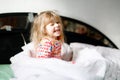 Little toddler girl having fun in bed after wake up. Healthy child jump and play hide and seek with parents. Adorable Royalty Free Stock Photo