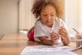 Little toddler girl laying down concentrate on drawing. Mix African girl learn and play in the pre-school class. Children enjoy Royalty Free Stock Photo