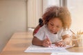 Little toddler girl laying down concentrate on drawing. Mix African girl learn and play in the pre-school class. Children enjoy