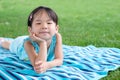 Little toddler girl laying on towel in the grass on a summer day Royalty Free Stock Photo