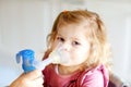 Little toddler girl making inhalation with nebulizer at home. Father or mother helping and holding the device. Child Royalty Free Stock Photo