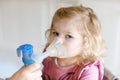 Little toddler girl making inhalation with nebulizer at home. Father or mother helping and holding the device. Child Royalty Free Stock Photo