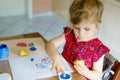 Little toddler girl painting with finger colors and potato stamp during pandemic coronavirus quarantine disease. Happy Royalty Free Stock Photo