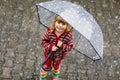 Little toddler girl playing with big umbrella on rainy day. Happy positive child running through rain, puddles Royalty Free Stock Photo