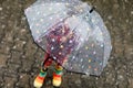 Little toddler girl playing with big umbrella on rainy day. Happy positive child running through rain, puddles Royalty Free Stock Photo