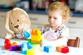 Little toddler girl with plush bunny playing with educational plastic colorful blocs toys. child having fun. Creative