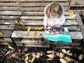 Little toddler girl reading magazine in the autumn garden