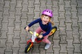 Little toddler girl running with balance bike on summer day. Happy child driving, biking with bicycle, outdoor activity