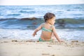 Little toddler girl sitting on the beach and looking at the waves. back view Royalty Free Stock Photo