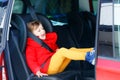 Little toddler girl sitting in car seat and looking out of the window on nature and traffic. Cute kid traveling by car Royalty Free Stock Photo