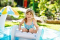 Little toddler girl splashing in an outdoors inflatable swimming pool on hot summer day. Happy healthy child enjoying sunny Royalty Free Stock Photo