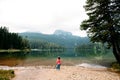 Little toddler girl stands and looks at Black Lake, Crno jezero, Durmitor, Montenegro. Nature and people. Wide angle. Royalty Free Stock Photo