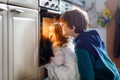 Little toddler girl and two kids boys baking, pizza or cookies in kitchen. Three children, siblings, brothers and sister