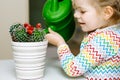 Little toddler girl watering flowers and cactus plants on window at home. Cute child helping, domestic life. Happy Royalty Free Stock Photo