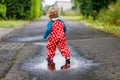 Little toddler girl wearing rain boots and trousers and walking during sleet, rain on cold day. Baby child having fun Royalty Free Stock Photo