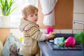 Little toddler helping in kitchen with washing dishes Royalty Free Stock Photo