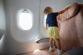 Little toddler on the plane stands on the passenger seat dangerous