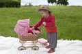 Little toddler playing with a pram outdoors Royalty Free Stock Photo