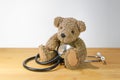 Little toddler teddy bear sitting on the table and playing with a stethoscope like a child, concept for pediatric medicine and