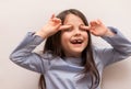 little toothless latina girl with long hair covered her eyes with her fingers Royalty Free Stock Photo