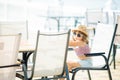 Little tourist girl wearing straw hat and sunglasses sitting at the outdoors restaurant, sea at the background Royalty Free Stock Photo