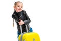 Little tourist with hand on chin holding yellow wheel suitcase