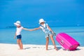 Little tourists girls with big suitcase on tropical white beach. Travel concept. Royalty Free Stock Photo