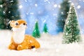 little toy deer sitting in the snow in the forest, greeting card, copy space Royalty Free Stock Photo