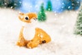 little toy deer sitting in the snow in the forest, greeting card, copy space Royalty Free Stock Photo
