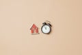 Little toy house and alarm clock on stark white background