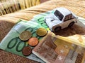 Little toy white car and euro money. Concept of the expensiveness of buying a new car, affordability of buying an old