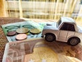 Little toy white car and euro money. Concept of the expensiveness of buying a new car, affordability of buying an old