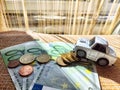 Little toy white car and euro money. Concept of the expensiveness of buying a new car, affordability of buying an old