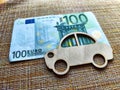 Little toy wooden car and euro money. Concept of the expensiveness of buying a new car, affordability of buying an old