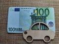 Little toy wooden car and euro money. Concept of the expensiveness of buying a new car, affordability of buying an old