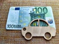 Little toy wooden car and euro money. Concept of the expensiveness of buying a new car, affordability of buying an old