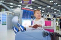 Toddler boy child holding passport with suitcase, sitting on trolley at airport, waiting for departure Royalty Free Stock Photo