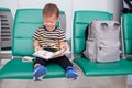 Cute smiling little Asian 30 months / 2 years old toddler boy child having fun reading a book while waiting for his flight at gate Royalty Free Stock Photo