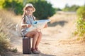 Little traveler studies the map while sitting on the old suitcase Royalty Free Stock Photo