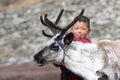 Little tsaatan boy playing with his family`s reindeer.